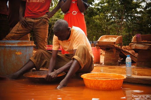 A small-scale gold miner in Tanzania mixes mercury, gold, and water by hand.